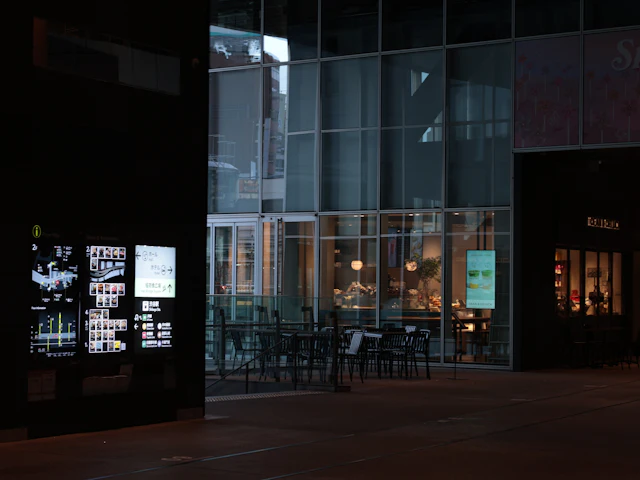 A lit floor-map directory screen standing outside a glass-fronted café at night.