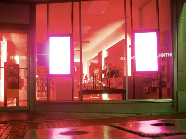 Two portrait screens glowing behind a shop window at night.